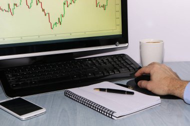Yatırımcı grafikler görünüyor ve defterindeki çiziminden kalemle notlar alır. Sonraki bir smartphone olduğunu
