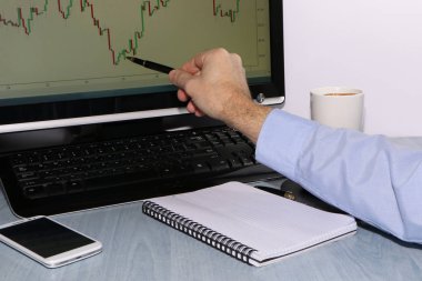 Yatırımcı grafikler görünüyor ve defterindeki çiziminden kalemle notlar alır. Sonraki bir smartphone olduğunu