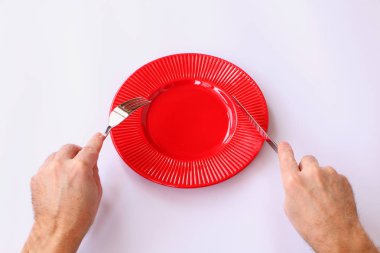 Yakın çekim-kırmızı plaka beyaz bir arka plan üzerinde. Onun el bir bıçak ve çatal.