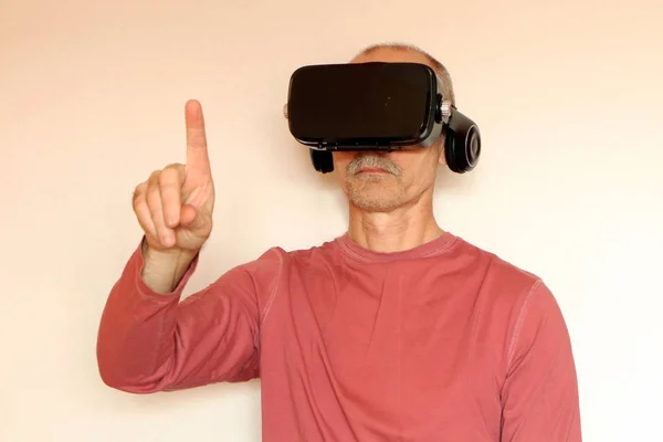 Close-up de um homem em uma camiseta rosa com óculos de real virtual — Fotografia de Stock