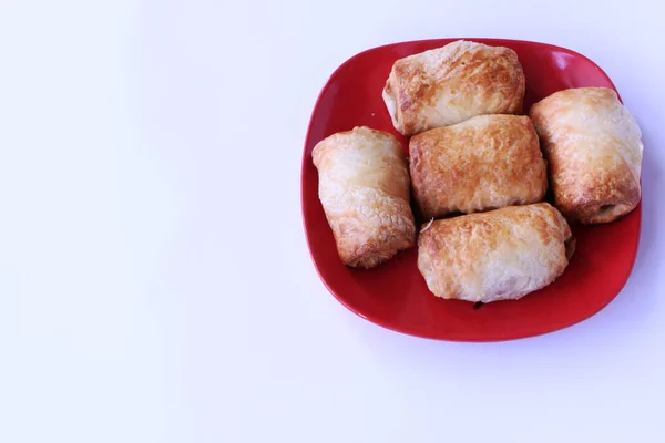 Primer plano: los pasteles fritos se encuentran en un plato rojo. El fondo es blanco —  Fotos de Stock