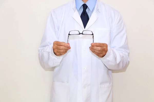 Optometrista de casaco branco segurando óculos em sua mão — Fotografia de Stock