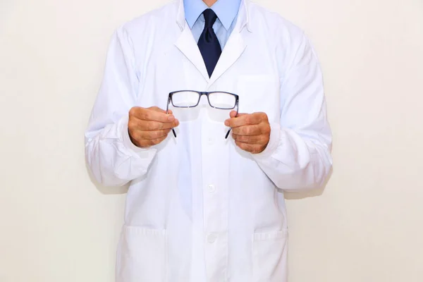 Optometrista de abrigo blanco con gafas en la mano — Foto de Stock