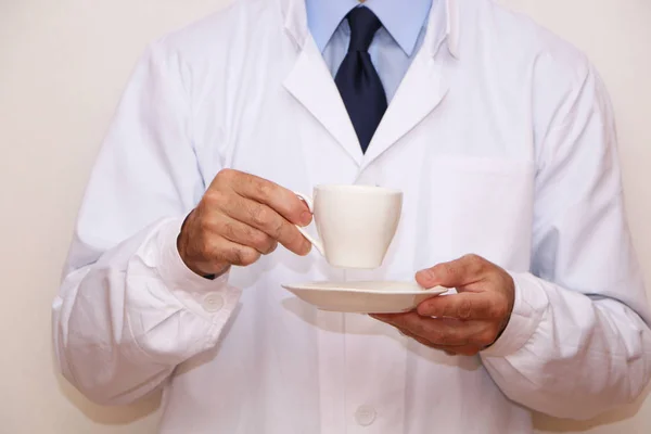 Primer plano: el médico sostiene en su mano una taza de café — Foto de Stock