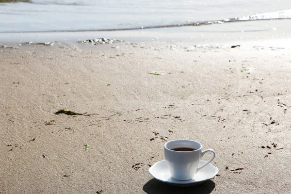 Ένα φλιτζάνι καφέ στέκεται στην αμμώδη παραλία — Φωτογραφία Αρχείου
