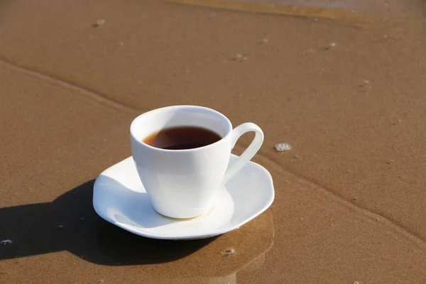 A cup of coffee stands on the sandy seashore — Stock Photo, Image