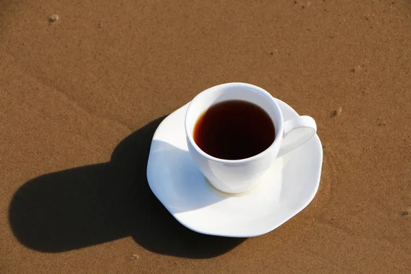 Eine Tasse Kaffee steht am sandigen Meeresufer — Stockfoto
