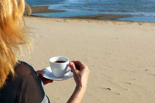 Meisje met een croissant en een kop koffie aan zee — Stockfoto