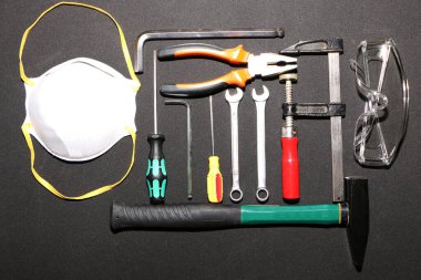 Siyah arka planda yeni el aletleri, maske, gözlük ve eldivenler. Siyah arka planda güvenli bir iş için yeni el aletleri ve koruyucu ekipmanlar..