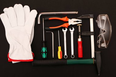 Siyah arka planda yeni el aletleri, maske, gözlük ve eldivenler. Siyah arka planda güvenli bir iş için yeni el aletleri ve koruyucu ekipmanlar..