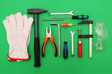Yeşil arka planda yeni el aletleri, maske, gözlük ve eldivenler. Yeşil arka planda güvenli bir iş için yeni el aletleri ve koruyucu ekipmanlar..