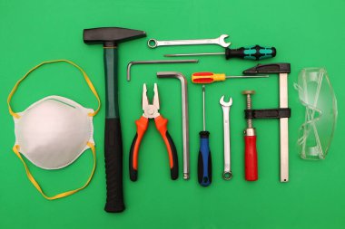 Yeşil arka planda yeni el aletleri, maske, gözlük ve eldivenler. Yeşil arka planda güvenli bir iş için yeni el aletleri ve koruyucu ekipmanlar..