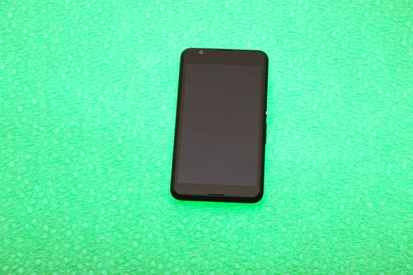 Zwarte Smartphone Ligt Een Heldergroene Achtergrond Achtergrond Wordt Hieronder Belicht — Stockfoto