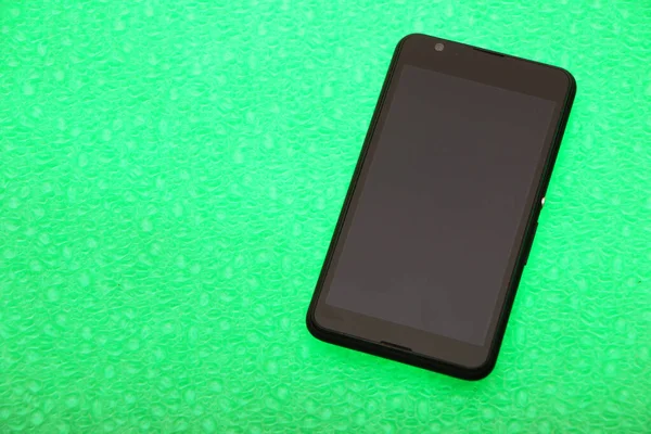 Czarny Smartfon Leży Jasnym Zielonym Tle Tło Przedstawiono Poniżej Widok — Zdjęcie stockowe