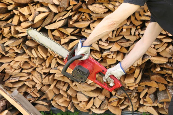 Man sawing wood with electric saw.  Close-up - of woodcutter sawing chain saw in motion.