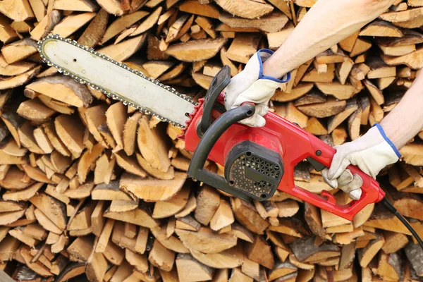 Man sawing wood with electric saw.  Close-up - of woodcutter sawing chain saw in motion.