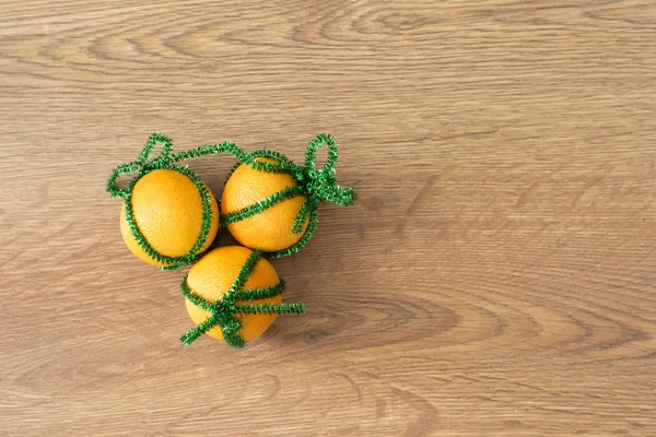 Yeni yıl. Noel zamanı. Yapay ağaçların yeşil kablosunda mandalinalar. Yeni yıl. Noel zamanı. Çam kozalaklarıyla çevrili.