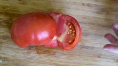 Kırmızı olgun domates Orta boy bir yeşil salata ve diğer yemekler için tahta kesme bir bıçak ile kesmek