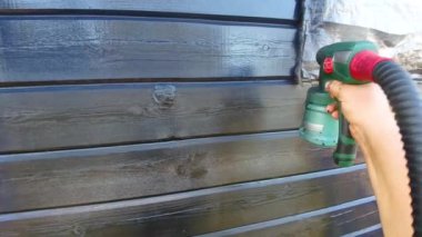 Siyah sprey boya kuru yaz hava dışında yükseklikte bir çubukla ahşap ev boyama