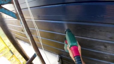 Siyah sprey boya kuru yaz hava dışında yükseklikte bir çubukla ahşap ev boyama