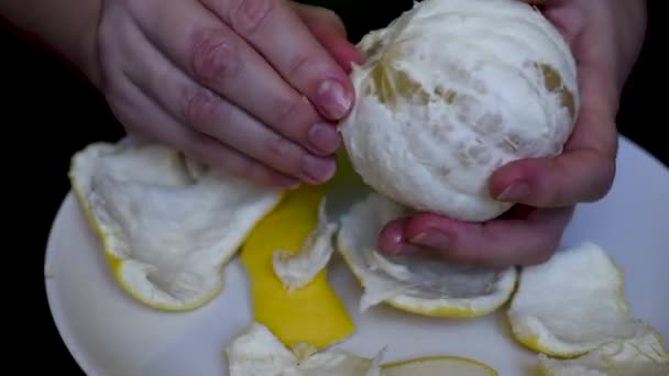 Esfolando Uma Toranja Suculenta Branca Com Mãos Uma Chapa Branca — Vídeo de Stock