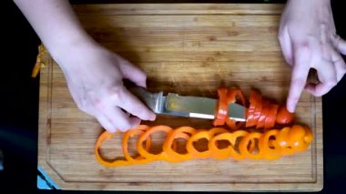 Olgun yüzük dolmalık biber yatıyordu çıkmadan deseni ve rastgele renkli bir bıçak ile kesmek