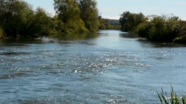 Soğuk su ve güçlü akım ile tam akan nehir yeşil bankalar üzerinde arka plan bahar 