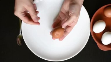 Tavuk yumurtası evde yumurta kabuğunun ellerini farklı renkleri beyaz ve kahverengi siyah bir tablo üzerinde beyaz bir tabakta yumurta yumurta kabuğu kaldırmak.