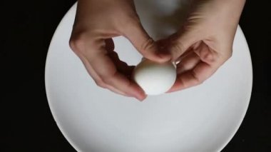Farklı renkleri beyaz ve kahverengi siyah bir tablo üzerinde beyaz bir tabakta yumurta yumurta kabuğu kaldırmak