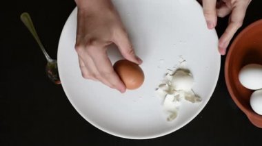 Farklı renkleri beyaz ve kahverengi siyah bir tablo üzerinde beyaz bir tabakta yumurta yumurta kabuğu kaldırmak
