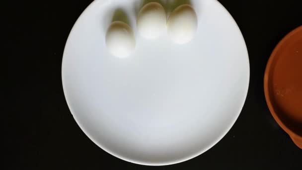 硬煮鸡卵旋转和摆动在一个白色的盘子 站在一个黑色的桌子上 — 图库视频影像