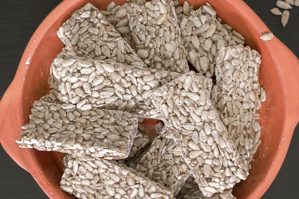 Tatlı, tek tek tatlı tohumların üzerine serpiştirilmiş killi tabağın üzerine serpilmiş lezzetli ayçiçeği tohumlarından yapılır. Vejetaryenlik, diyet, sağlıklı yiyecekler. Bal ya da şeker şurubuyla doldurulmuş ayçiçeği tohumları tüketime hazır.