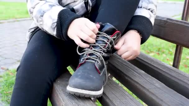 Dětské Vázání Tkaničky Černé Kožené Boty Zatímco Sedí Lavičce Ulici — Stock video