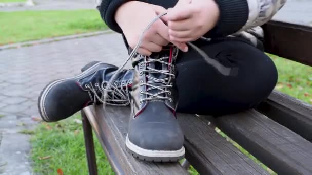Gyermek Fekete Bőr Csizma Cipőfűző Árukapcsolás Egy Utcai Padon Parkban — Stock videók