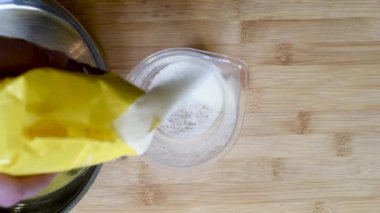 Ölçüm plastik oranı ölçmek için fincan irmik ekleyin ve sonra karıştırın malzemeyi Ahşap mutfak tezgah ile 
