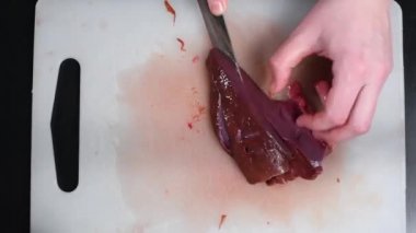 Kesme ve bir siyah saplı bir bıçak ile gemide bir sığır eti karaciğer parçası yendi. Karaciğer üzerinden pişirme biftek için. Üstten Görünüm 