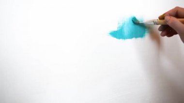 Düz fırçalar ile tuval üzerinde mavi yağlı boya ile beyaz bir tuval üzerine resim olan sanatçı boyalar çeşitli vuruş uygulanan. Yakın çekim çekim 