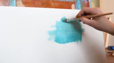 Düz fırçalar ile tuval üzerinde mavi yağlı boya ile beyaz bir tuval üzerine resim olan sanatçı boyalar çeşitli vuruş uygulanan. Yakın çekim çekim 