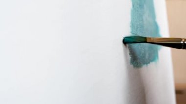 Düz fırçalar ile tuval üzerinde mavi yağlı boya ile beyaz bir tuval üzerine resim olan sanatçı boyalar çeşitli vuruş uygulanan. Yakın çekim çekim 