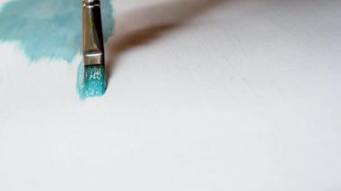 Düz fırçalar ile tuval üzerinde mavi yağlı boya ile beyaz bir tuval üzerine resim olan sanatçı boyalar çeşitli vuruş uygulanan. Yakın çekim çekim 