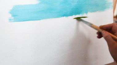 Sanatçı gelecekteki resim için temel oluşturma düz fırça ile konturları uygulama üzerine yağlı boya, Yağlıboya Resim boyar. Mavi gökyüzü ve yeşil 