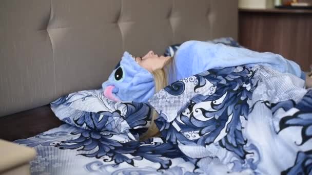 女孩穿着蓝色睡衣躺在床上与猫玩耍 并把猫抱在怀里 抚摸着躺在女孩胸前的猫 发出呼噜声 — 图库视频影像