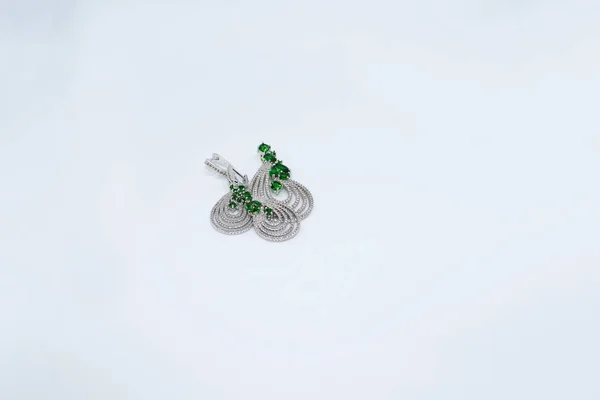 Beyaz bir arka plan üzerinde mücevher, küpe, kolye, yeşil taşlar ve kristaller ışıkta ışıltılı 