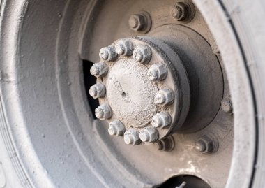Otobüsün arka tekerleğinin hub 'ı veya cıvata ve fındık ile büyük bir makine, yol çamur kum ve tuz karışımı ile kaplı otobüs çarkı hub 'ın gün ışığında taşıyan kirli tekerlek