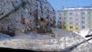 Eski araba retro ön cam silecekleri donmuş kar ve buz kristalleri araba ön cam temiz. Yüksek binaların arka planında sabah arabanın ön camını ön cam silecekleri ve yıkayış sıvısı ile buzdan temizleme