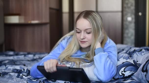 パジャマで長い髪を持つ女の子は ベッドで休んで朝 ノートパソコンを見て コーヒーを飲んで マシュマロを食べる — ストック動画