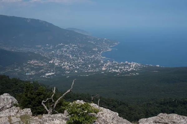 The sea and the city from the mountains from the bird\'s eye view of the beautiful blue sea of water reflecting the clouds on the background of green mountains and South of the city Sea city on the background of greenery and the sea in the afternoon