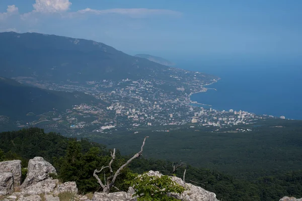 The sea and the city from the mountains from the bird\'s eye view of the beautiful blue sea of water reflecting the clouds on the background of green mountains and South of the city Sea city on the background of greenery and the sea in the afternoon