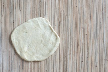 Mutfak masasındaki hamur hamuru merdaneyle rulo haline getirilir. Doldurulmuş bir turta yapmak için. Masanın yüzeyinde hamur pastası var.