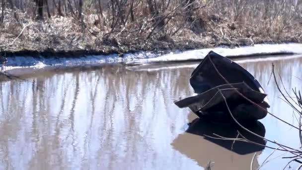 一辆老黑轿车的机翼被撕下 漂浮在一条坏路上的水坑里 在明亮的日光下 汽车机翼的内部部分在没有沥青的情况下 在水坑中 — 图库视频影像